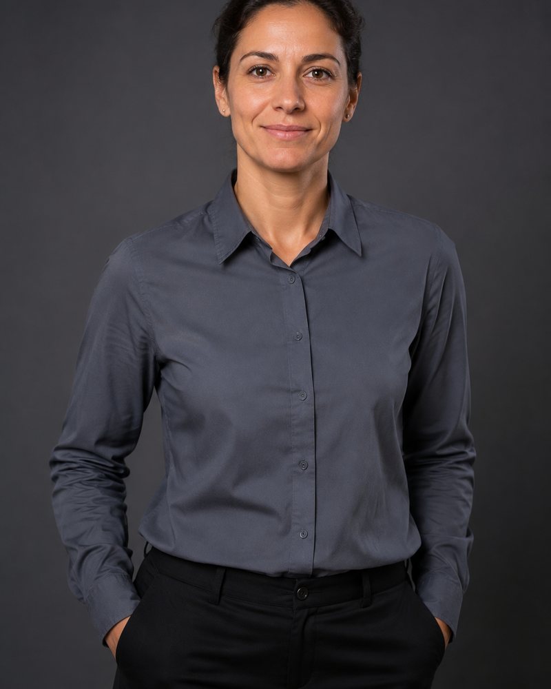 Retrato de estúdio de mulher de camisa de trabalho cinzenta, cabelo apanhado, fundo cinzento escuro